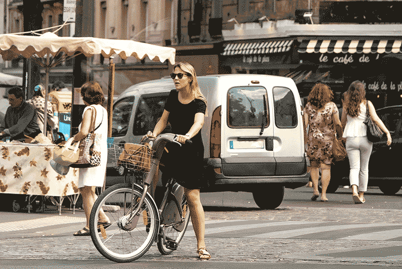 woman on her ebike, looking around a city market in Europe
